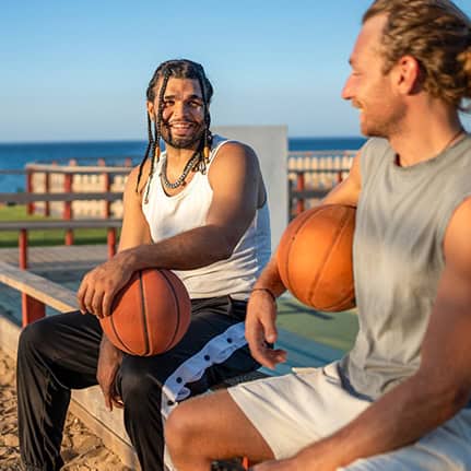 two guys sitting with basketballs