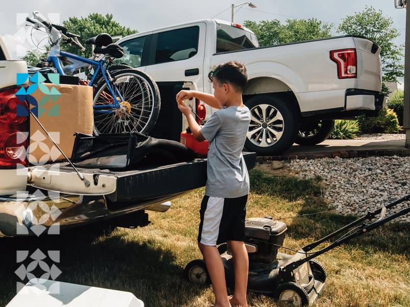 child at the back of a truck with his bike