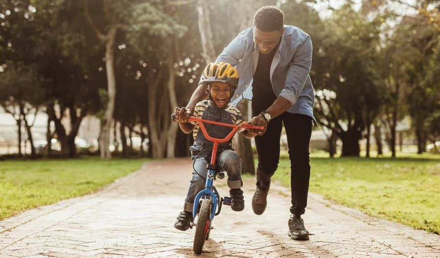parent teaching child how to ride a bike